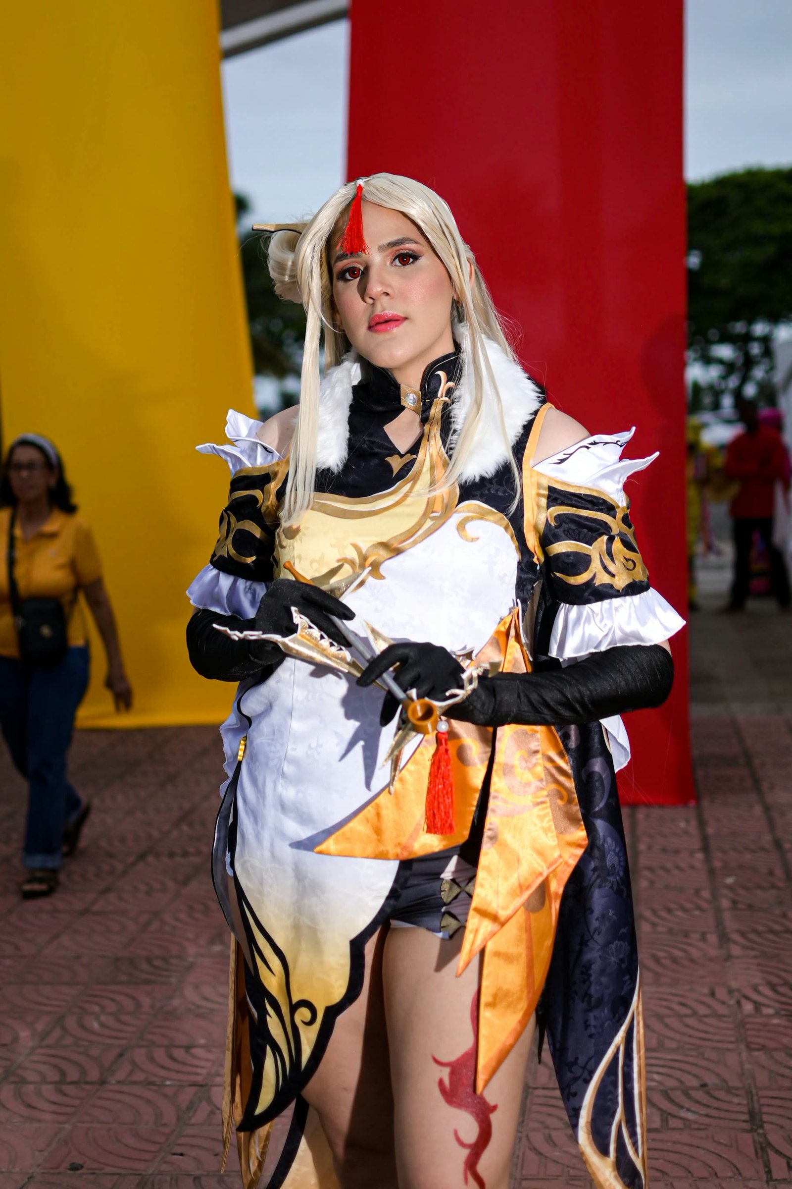 A cosplayer in an elaborate white-and-gold costume