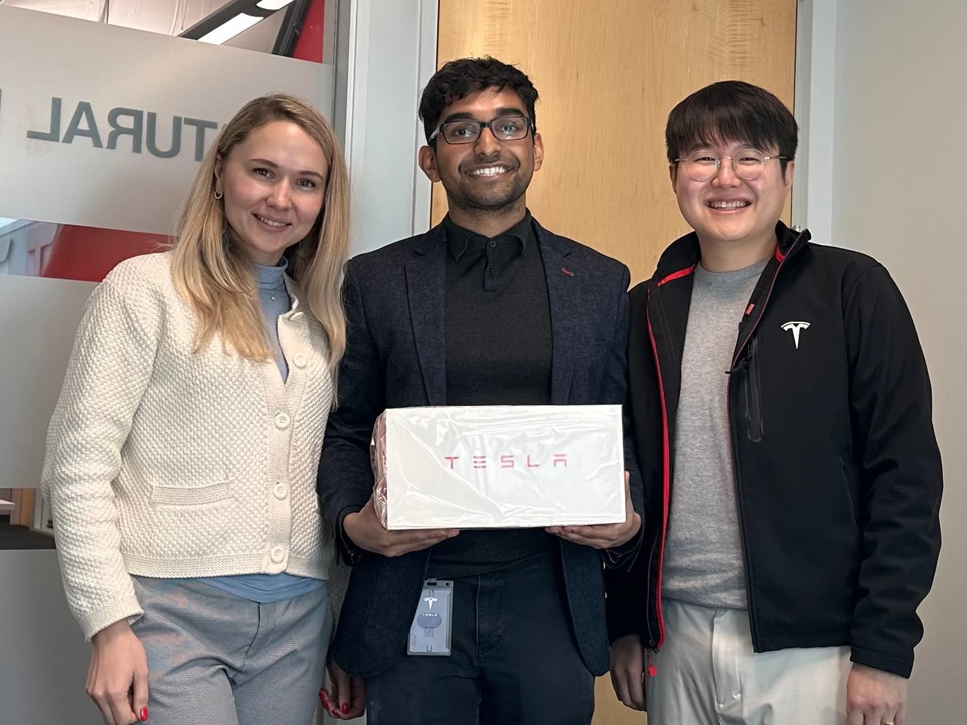 Nabeen with two Tesla colleagues, holding a Tesla-boxed farewell gift
